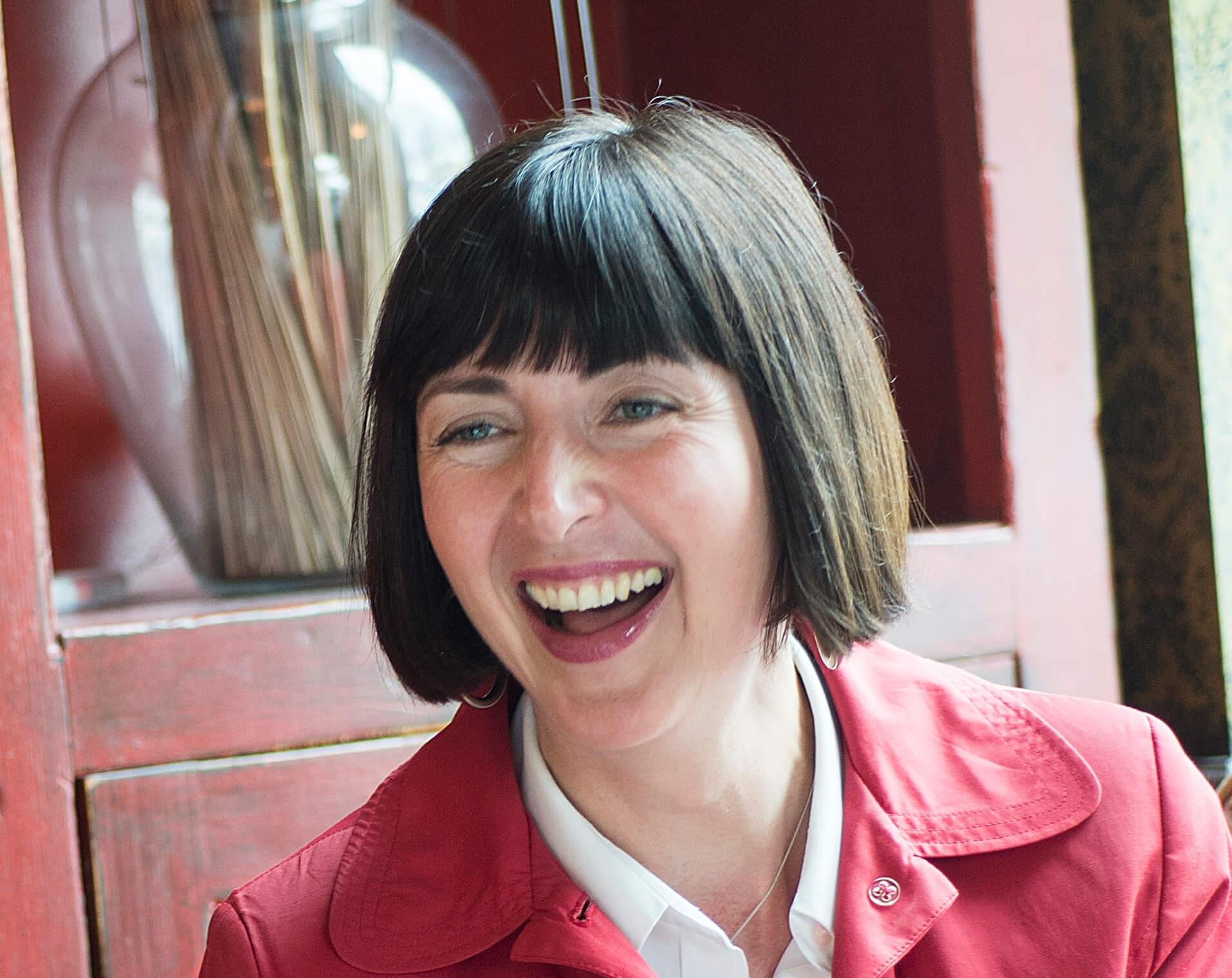 Jo Maughan, career coach, smiling, in a red coat